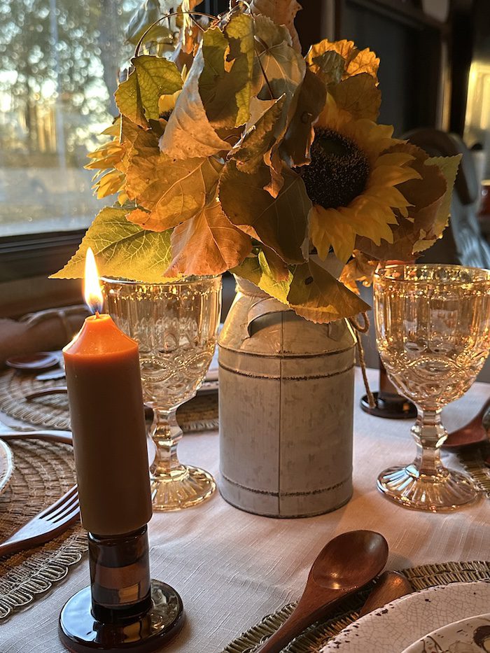 A cozy table setting with sunflowers, a lit candle, and wine glasses.